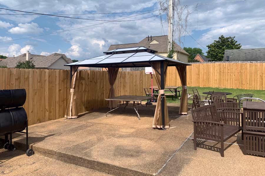 new pergola with shaded seating next to freshly built wood fencing by local contractor backyard specialist in olive branch mississippi