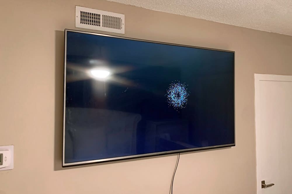 television display with cord hanging after professional tv mounting service in apartment bedroom near bluff city tennessee.