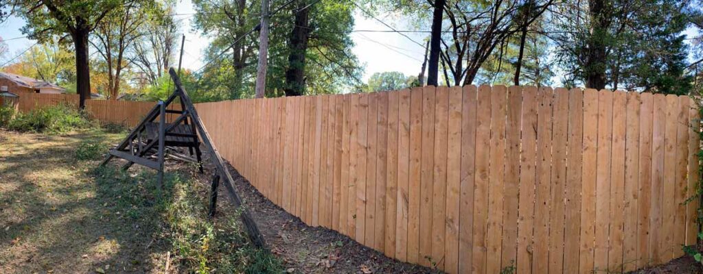 wide angled view of long and tall cedar picket privacy fencing installed next to backyard swingset by 1 handy craftsman in olive branch mississippi