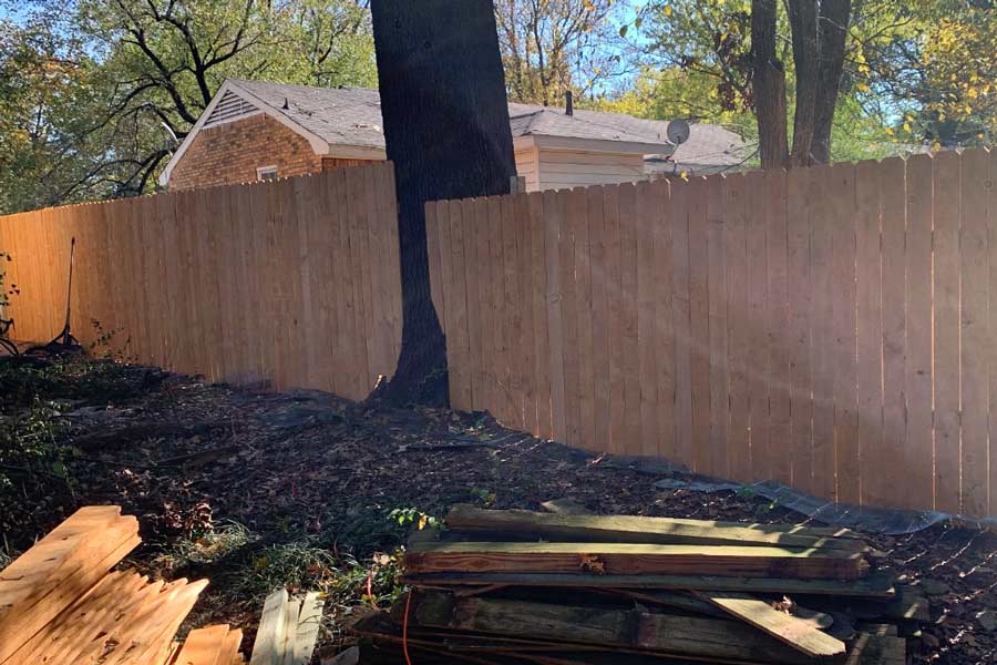 old fence pickets taken down in a pile next to new cedar wood picket and frame installation job by 1 handy craftsman fencing pro near memphis tennessee