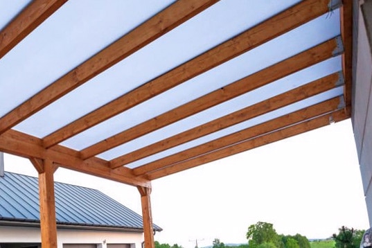 pergola attached to the side of mississippi barn on acreage land outside olive branch with 20 foot cedar wood beams and custom fabric shade by quality handyman services carpentry