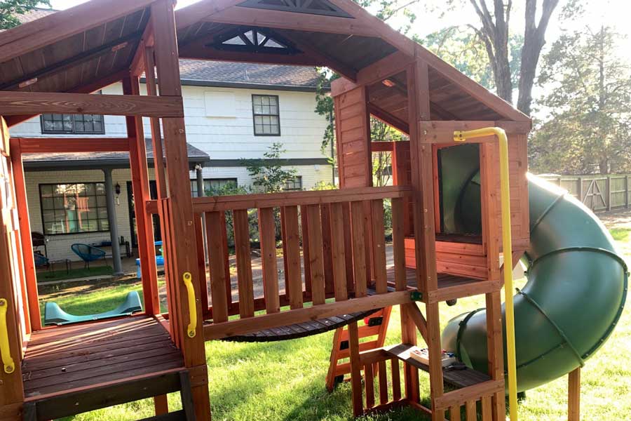 inside look at kids playground with bouncy bridge and swirly slide in homeowners backyard near germantown tennessee