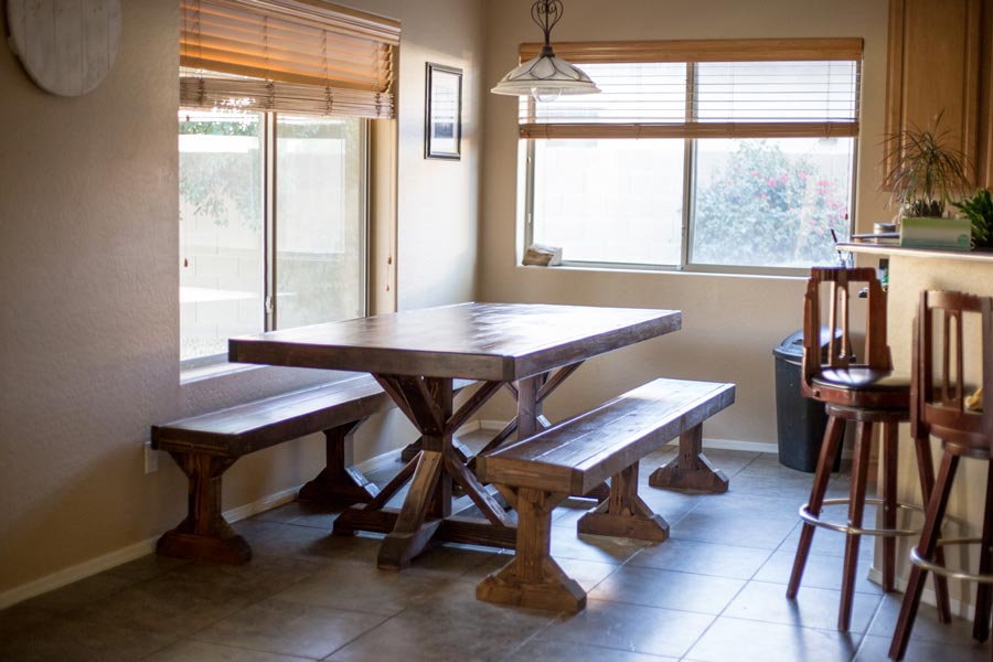 espresso stained and finished wooden farmhouse table with custom matching bench seating in corner of kitchen by furniture building craftsman that offers handyman services in olive branch ms