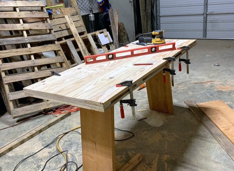 table building process in desoto county wood shop clamps and level next to pallet boards used to create furniture