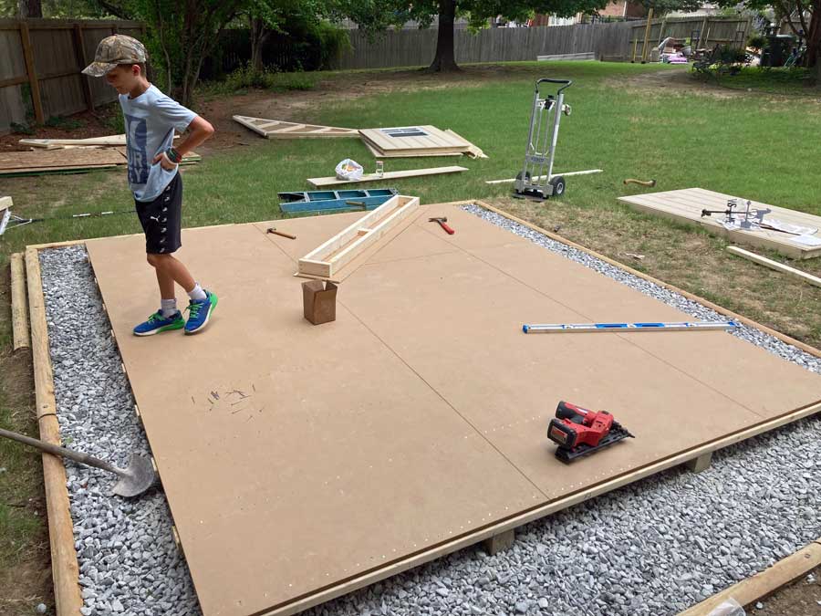 Son of carpenter standing on finished shed decking and flooring before framing up walls for local homeowner backyard project in cordova, TN.