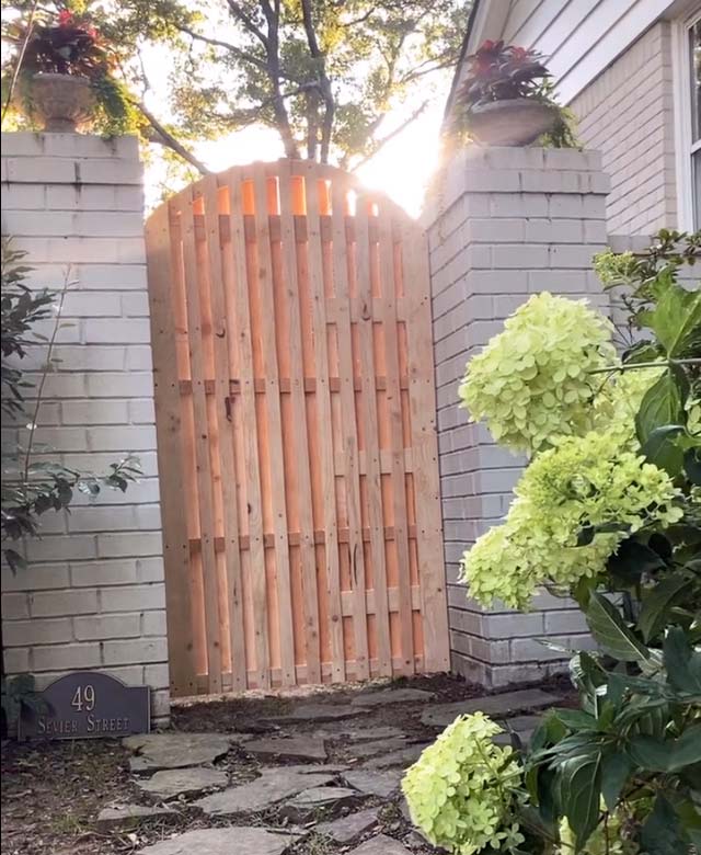 outside look from front of Midtown Memphis residence off sevier and walnut grove to show new cedar wood gate with arch thin design for privacy between brick wall by 1 Handy Craftsman