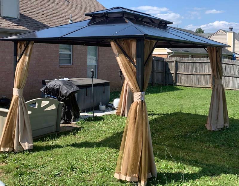 assembled backyard gazebo anchored to ground with screw stakes with curtains installed near horn lake mississippi