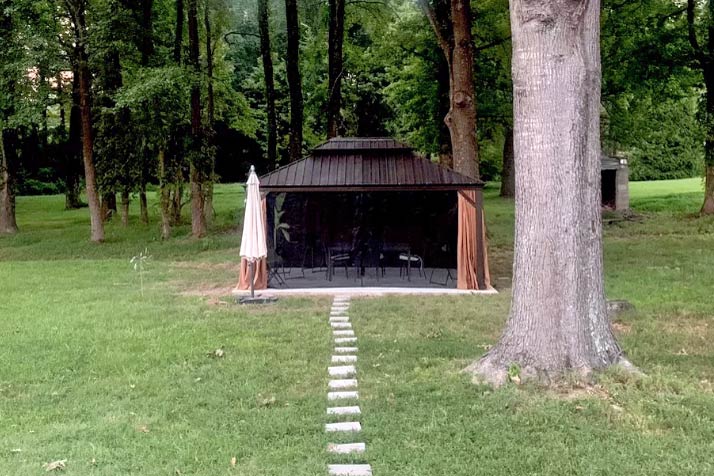 stone paver path from back screen patio out to newly built metal gazebo with bug net and fabric curtains patio furniture assembled by olive branch handyman near Memphis